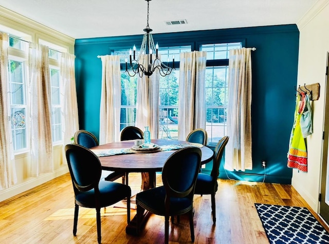 dining area with wood finished floors, crown molding, visible vents, baseboards, and a chandelier