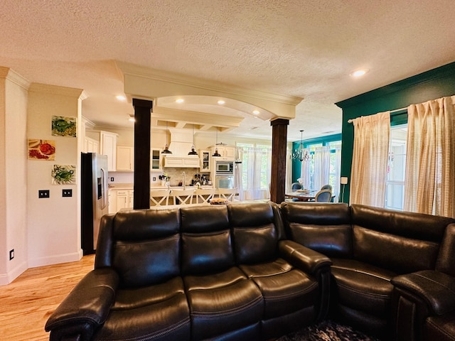 living area featuring ornamental molding, light wood-type flooring, and ornate columns