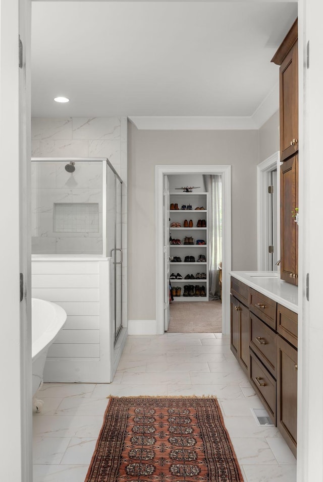 full bathroom with vanity, marble finish floor, a freestanding tub, a spacious closet, and a stall shower