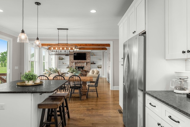 kitchen with freestanding refrigerator, a breakfast bar, a fireplace, open floor plan, and dark wood-style floors