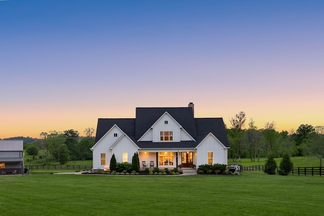 modern farmhouse style home featuring board and batten siding, a porch, a chimney, a front yard, and fence