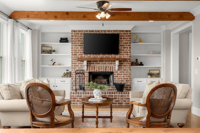 living room with built in features, a ceiling fan, beam ceiling, and a brick fireplace
