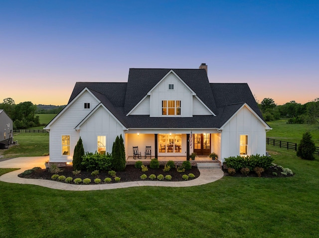 view of front of home with board and batten siding, a lawn, a chimney, and roof with shingles