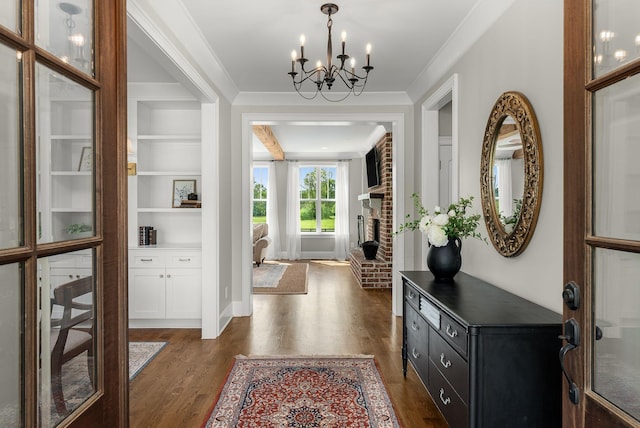 foyer entrance featuring an inviting chandelier, ornamental molding, and dark wood-style floors