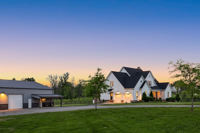 modern farmhouse style home with fence, a chimney, a front yard, and gravel driveway