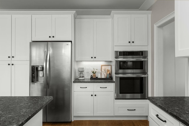 kitchen with dark stone counters, backsplash, stainless steel appliances, and white cabinetry