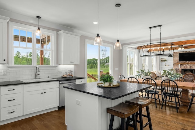 kitchen with a sink, dark countertops, white cabinets, and dishwasher