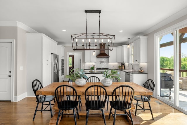 dining space featuring baseboards, recessed lighting, wood finished floors, and a chandelier