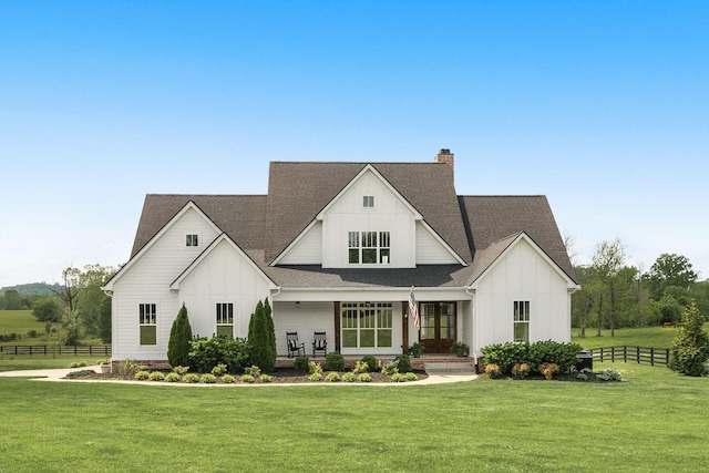 modern farmhouse style home with fence, roof with shingles, board and batten siding, a porch, and a front yard