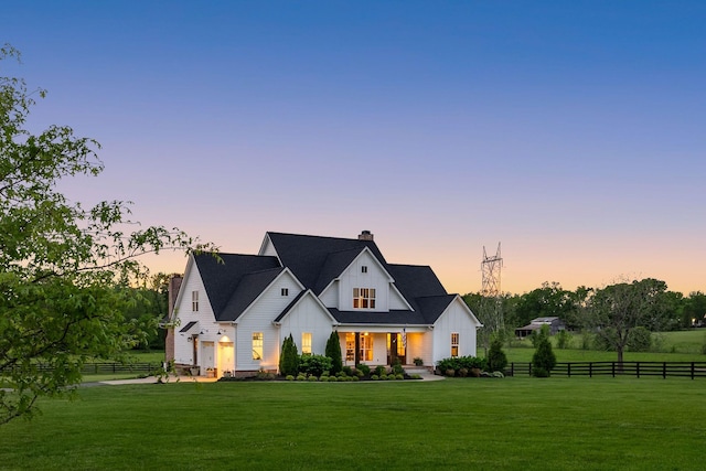 modern inspired farmhouse with fence, covered porch, a chimney, and a front yard