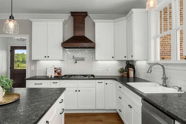 kitchen featuring white cabinets, a sink, stainless steel appliances, custom range hood, and tasteful backsplash