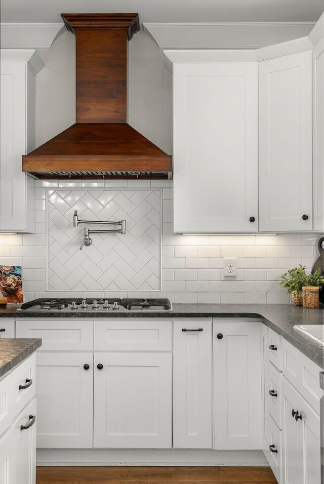 kitchen featuring white cabinetry, decorative backsplash, stainless steel gas stovetop, and premium range hood