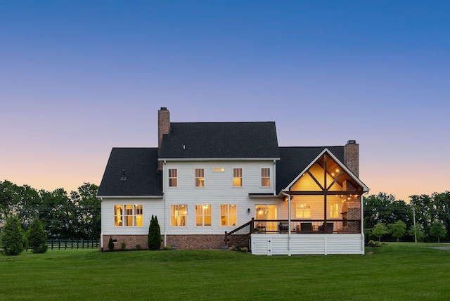 back of property at dusk featuring a lawn and a chimney