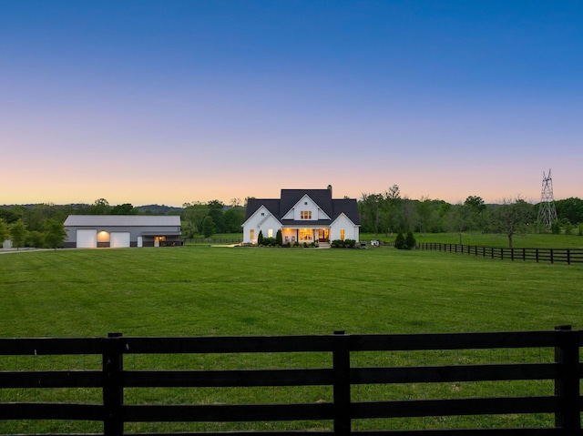 modern farmhouse with a garage, a fenced front yard, a yard, and a rural view