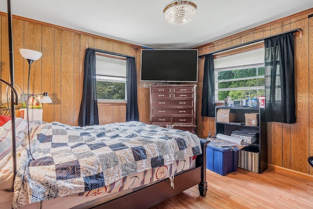 bedroom featuring multiple windows, wood walls, and wood finished floors