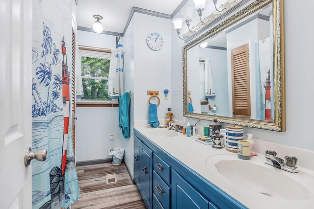 full bath featuring crown molding, a sink, wood finished floors, and double vanity