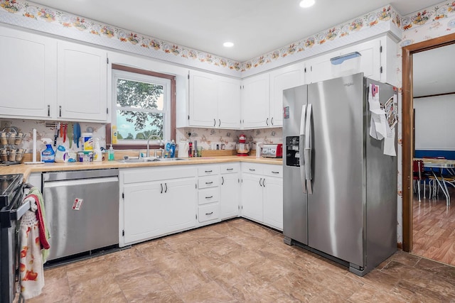 kitchen with appliances with stainless steel finishes, a sink, light countertops, recessed lighting, and white cabinetry