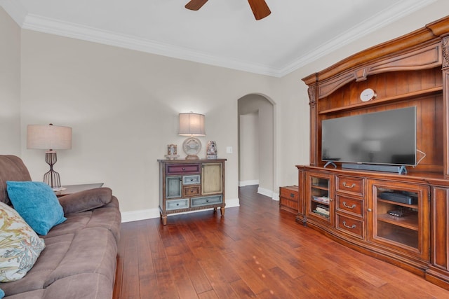 living area with ceiling fan, crown molding, arched walkways, baseboards, and dark wood-style floors