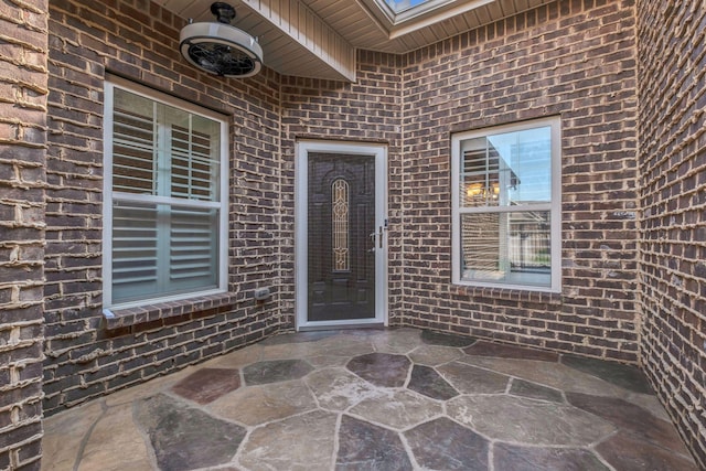 doorway to property featuring a patio and brick siding