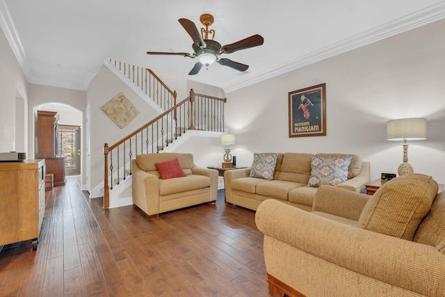 living area featuring a ceiling fan, crown molding, arched walkways, stairway, and dark wood-type flooring