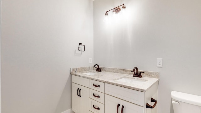 bathroom with double vanity, a sink, and toilet