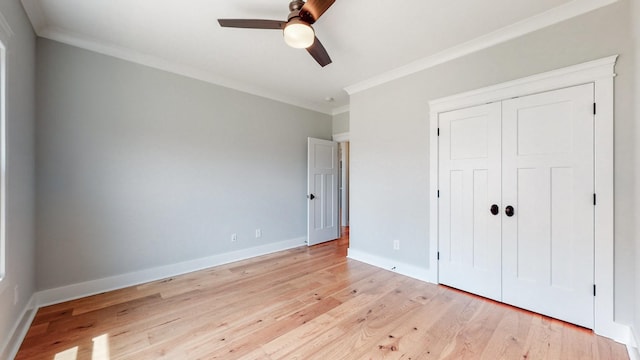 unfurnished bedroom with a ceiling fan, crown molding, light wood-type flooring, baseboards, and a closet