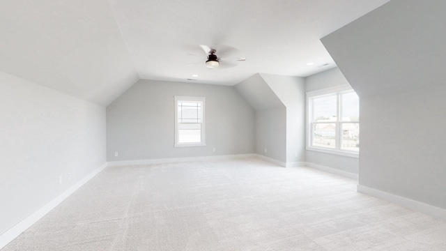 additional living space with light colored carpet, baseboards, ceiling fan, and vaulted ceiling