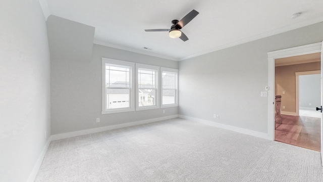 empty room with ceiling fan, visible vents, crown molding, baseboards, and carpet