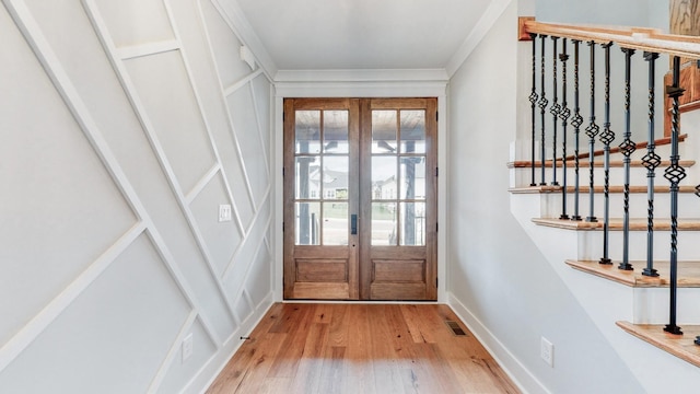 entryway with crown molding, visible vents, wood finished floors, baseboards, and french doors