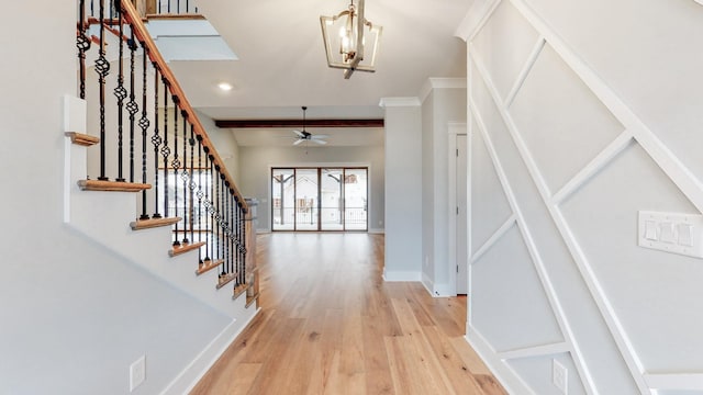 foyer featuring baseboards, ceiling fan with notable chandelier, light wood finished floors, and stairs