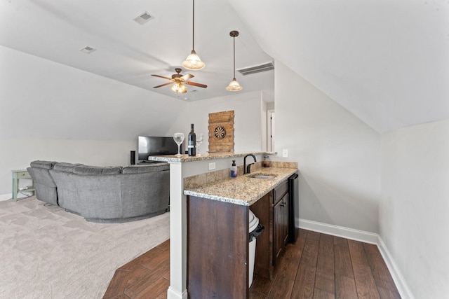 kitchen with a sink, baseboards, a peninsula, and lofted ceiling