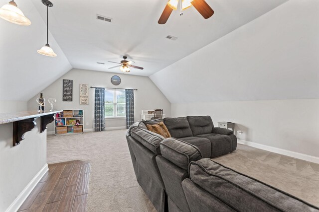carpeted living room featuring visible vents, baseboards, ceiling fan, and lofted ceiling