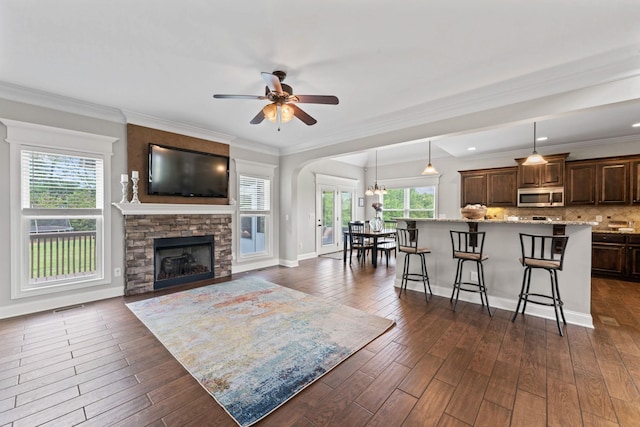 living room featuring visible vents, dark wood-style flooring, ceiling fan, and a fireplace