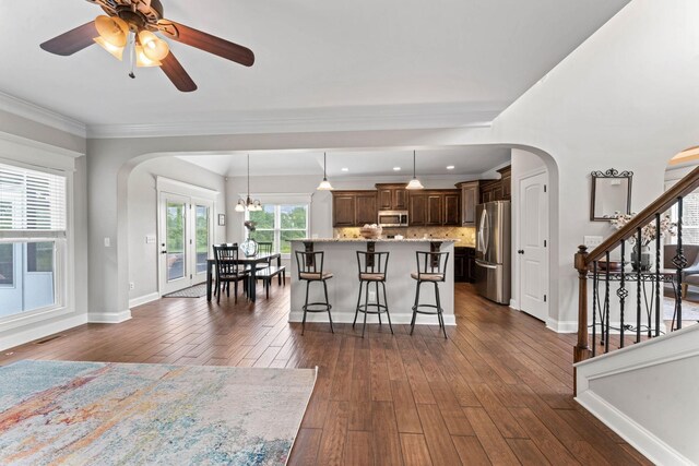 interior space with crown molding, arched walkways, dark wood-style flooring, and stairs