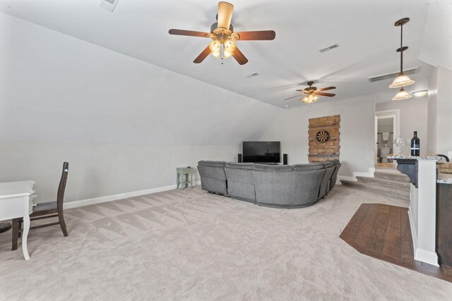 living room with visible vents, lofted ceiling, baseboards, ceiling fan, and light colored carpet