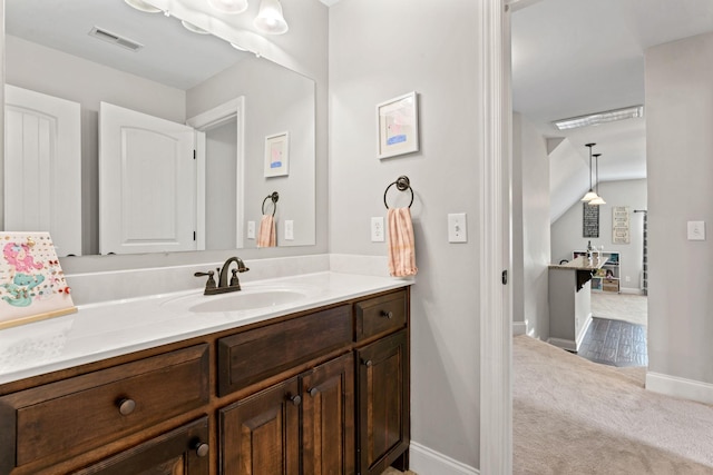 bathroom featuring baseboards, visible vents, lofted ceiling, and vanity
