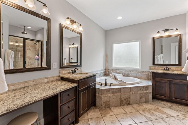 bathroom featuring a sink, tile patterned flooring, a bath, and two vanities