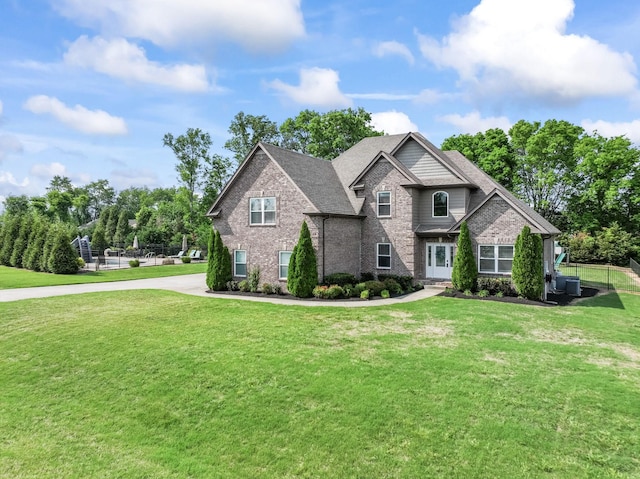 craftsman-style home featuring brick siding, a front lawn, roof with shingles, and fence
