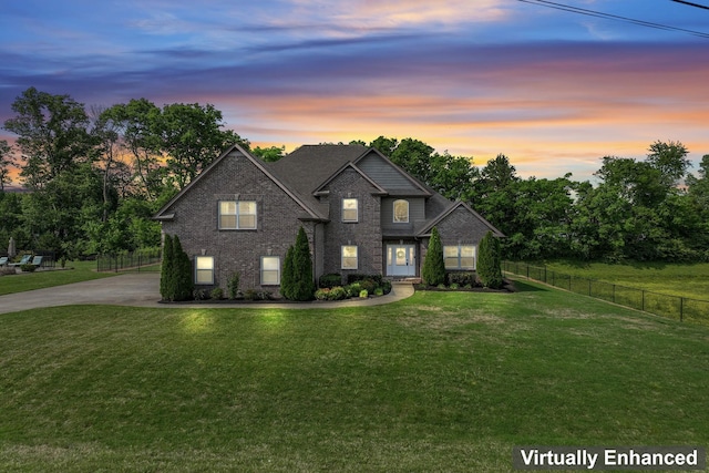 traditional-style home with a yard, brick siding, fence, and concrete driveway