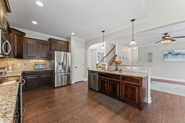 kitchen with dark wood-style flooring, dark brown cabinets, a sink, arched walkways, and stainless steel appliances
