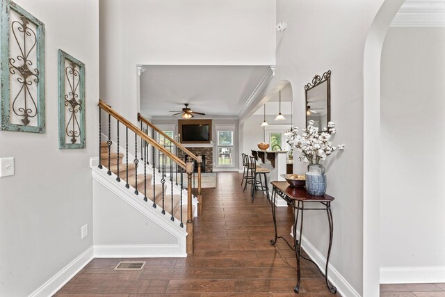 foyer featuring arched walkways, ceiling fan, baseboards, and a brick fireplace