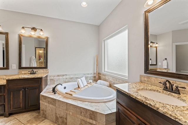 full bath featuring two vanities, a sink, and a garden tub