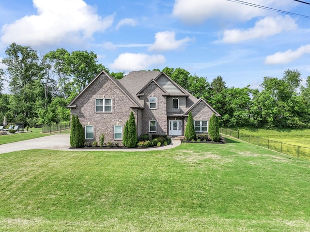 view of front of property with brick siding, a front lawn, fence, and concrete driveway