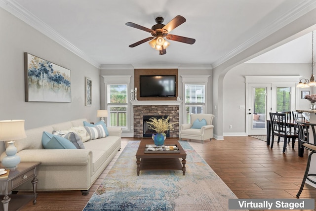 living room with a healthy amount of sunlight, ornamental molding, ceiling fan with notable chandelier, and wood finished floors