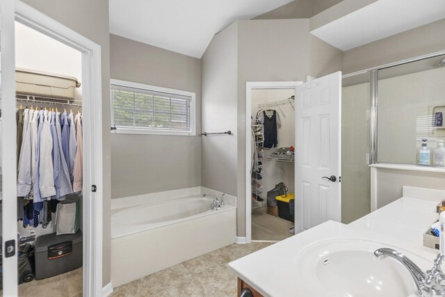 bathroom with a shower with door, a walk in closet, a garden tub, and vanity