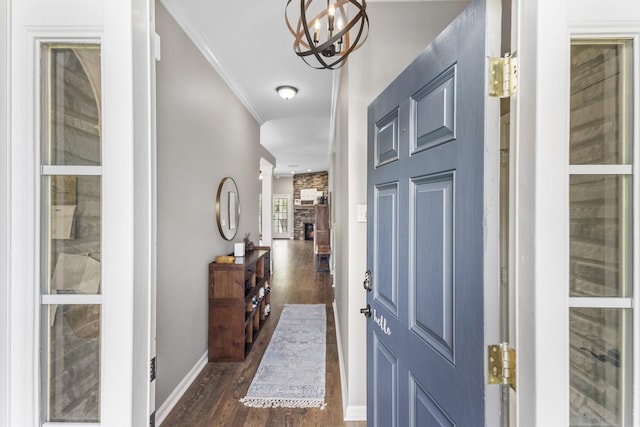 entryway featuring baseboards, ornamental molding, dark wood finished floors, and an inviting chandelier