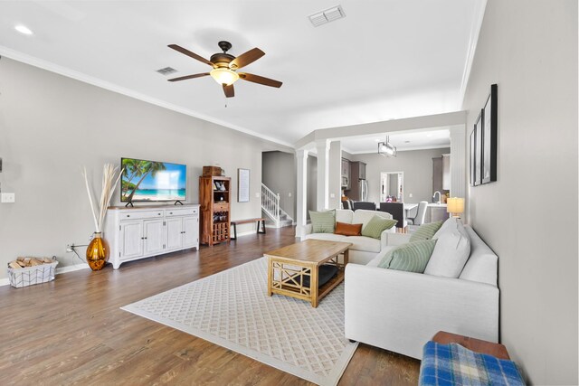 living area featuring visible vents, ornamental molding, stairs, and ceiling fan