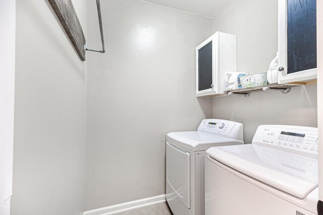 washroom with light tile patterned floors, baseboards, washing machine and dryer, and cabinet space