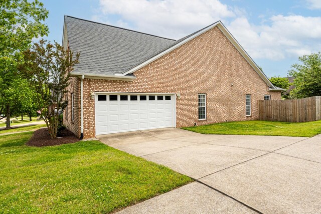 view of side of property with driveway, roof with shingles, a garage, brick siding, and fence