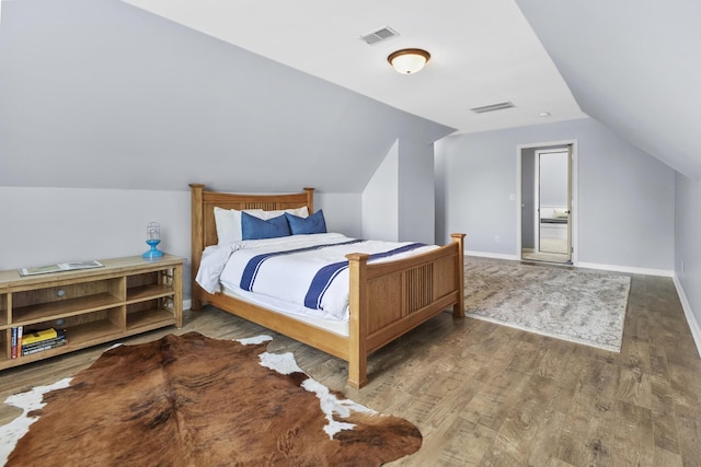 bedroom with baseboards, visible vents, wood finished floors, and vaulted ceiling